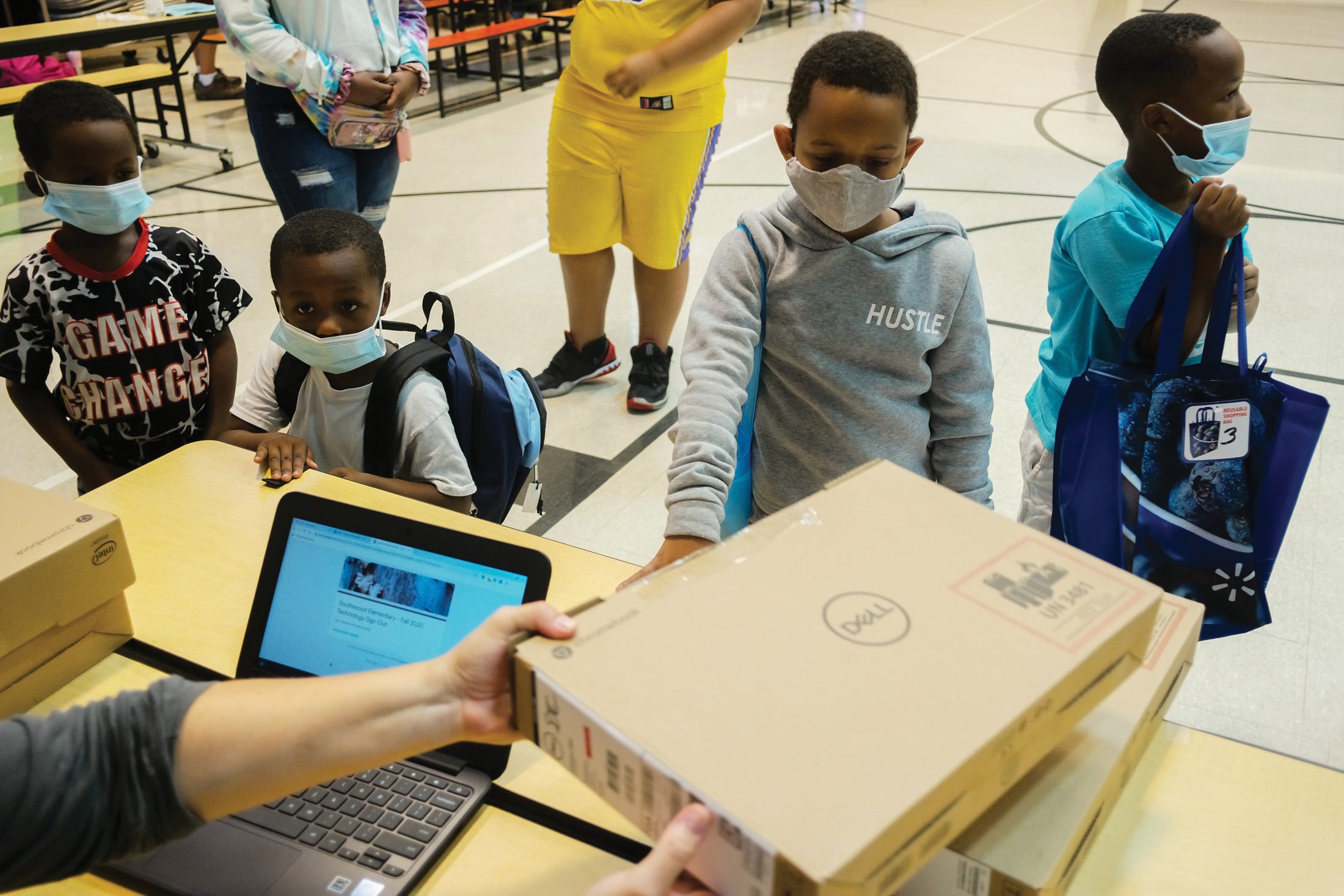 Students pick up computers before the start of the 2020-21 school year at Southwood Elementary School, part of Columbus City Schools.