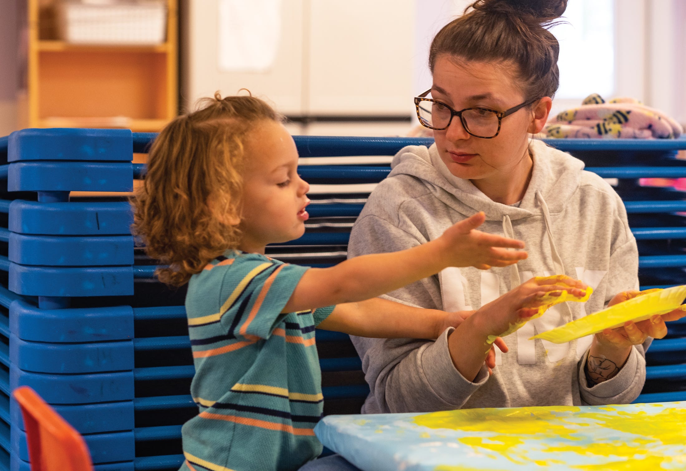 Teacher Lydia Fleming works on finger painting with Raiden Freeman at Almost Home Daycare in Newark.